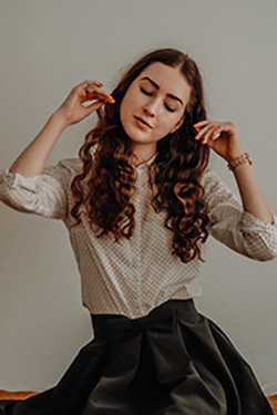 A woman dressed in a dotted tan version of the Oasis women's blouse sways to the music while sitting.