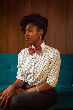 A woman dressed in a polka-dotted Oasis women's blouse and Oasis slacks looks into the distance.