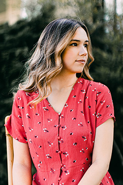 A woman dressed in a flamingo pink Oasis women's blouse smiles into the distance.