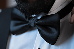 A black Oasis men's bow-tie is tied around a man for a wedding occasion.