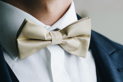 A creamish Oasis men's bow-tie is worn by a man heading to a special occasion.