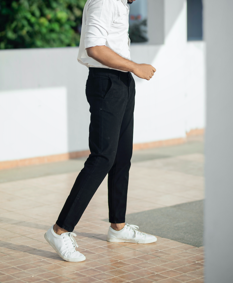 A man walks across a light brown tile floor in dark blue Oasis men's chino pants.