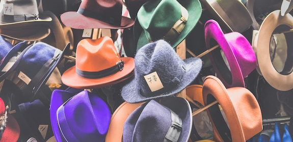 Hundreds of colorful fedora hats thrown on top of each other.