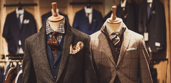 The mens section of the Oasis store displays two mannuequins dressed in a dark brown suit and a checkered grey suit.