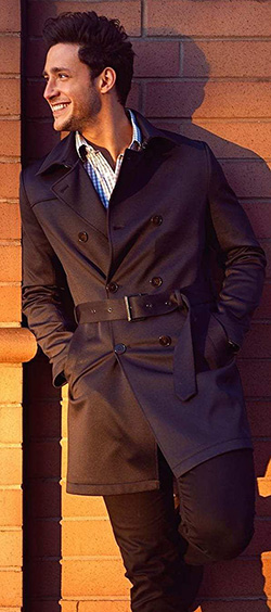 The Oasis Clothing visionary Doctor Mike smiles at the sunset while wearing a large black Oasis men's coat.