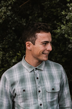 A man smiles into the distance while wearing a green-white Oasis men's plaid shirt.