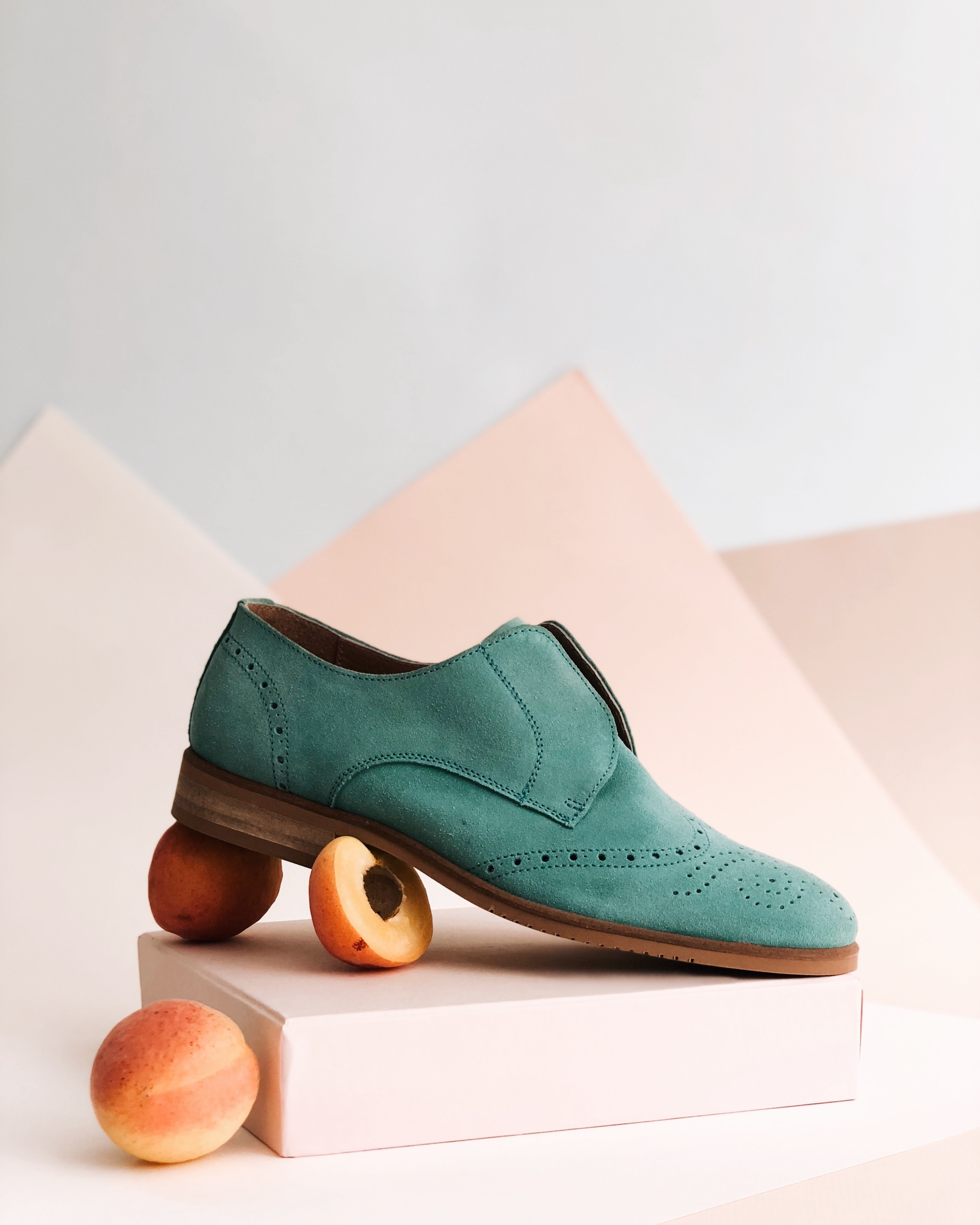 A teal-colored Oasis sneaker sits on top of slices of peaches.