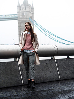 A woman leans against the railing while wearing striped gray Oasis women's slacks.