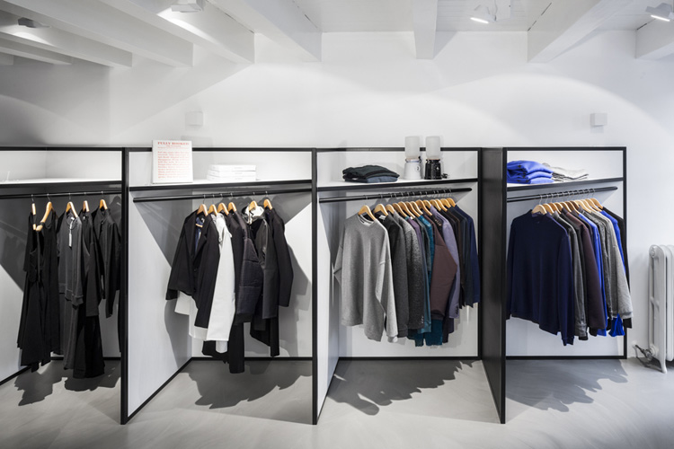 An Oasis Clothing store aisle is filled with colorful jackets and sweaters on white racks.